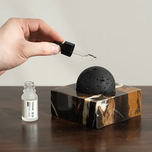 Hand placing the black volcanic stone onto the marble diffuser base