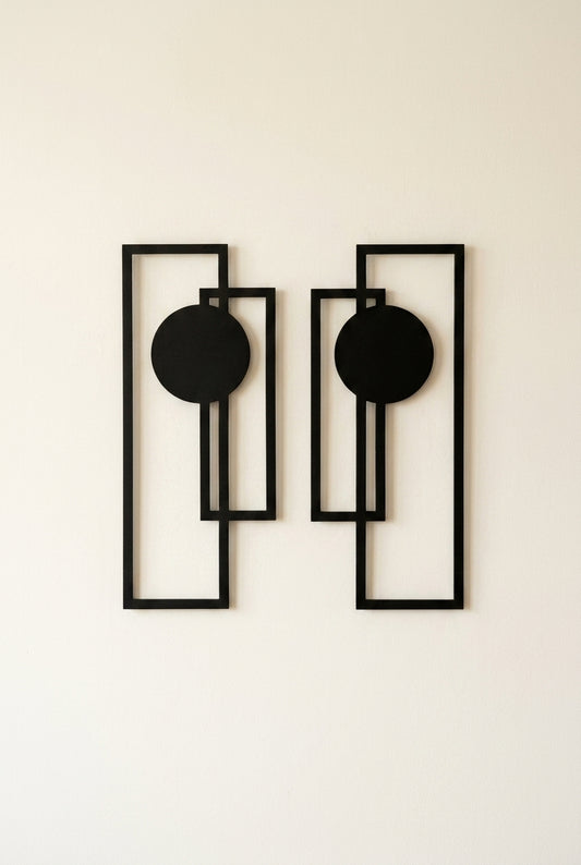 Set of 2 matte black geometric metal wall sculptures on a warm tan wall