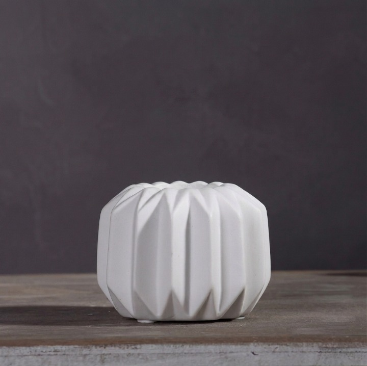 Small round white faceted porcelain tealight holder on a dark background