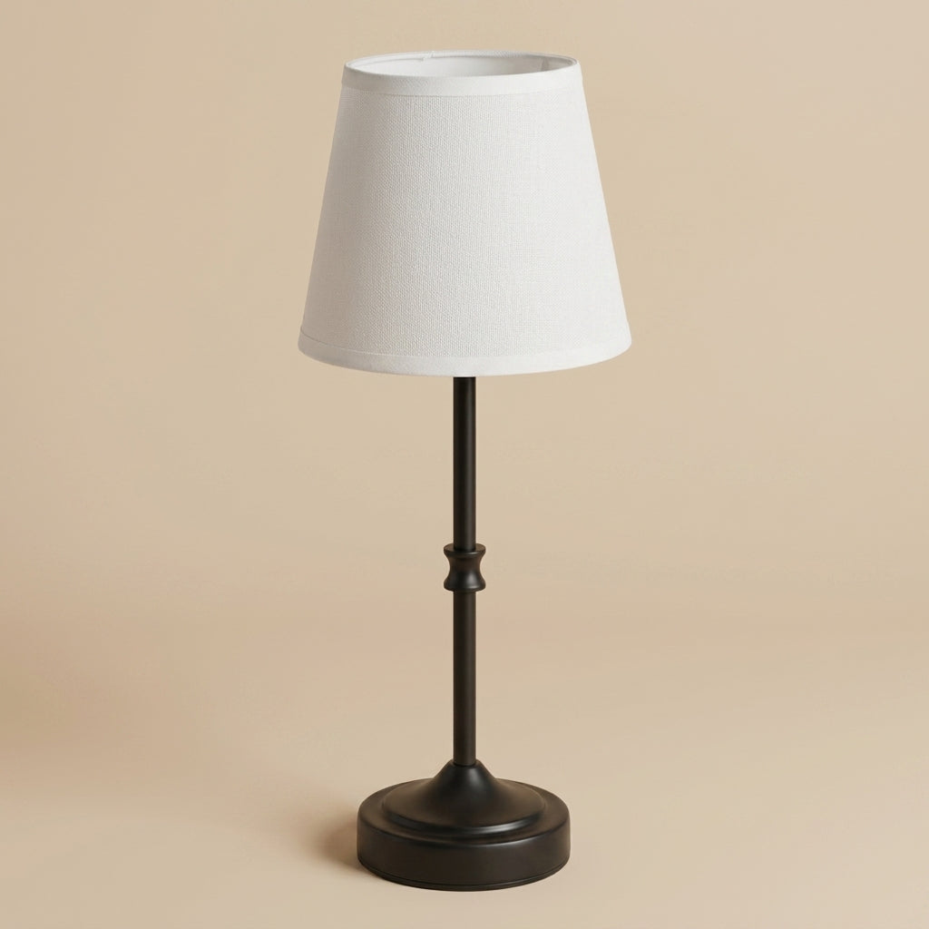 Cordless warm-glow table lamp with black metal base and white fabric shade on a warm beige background