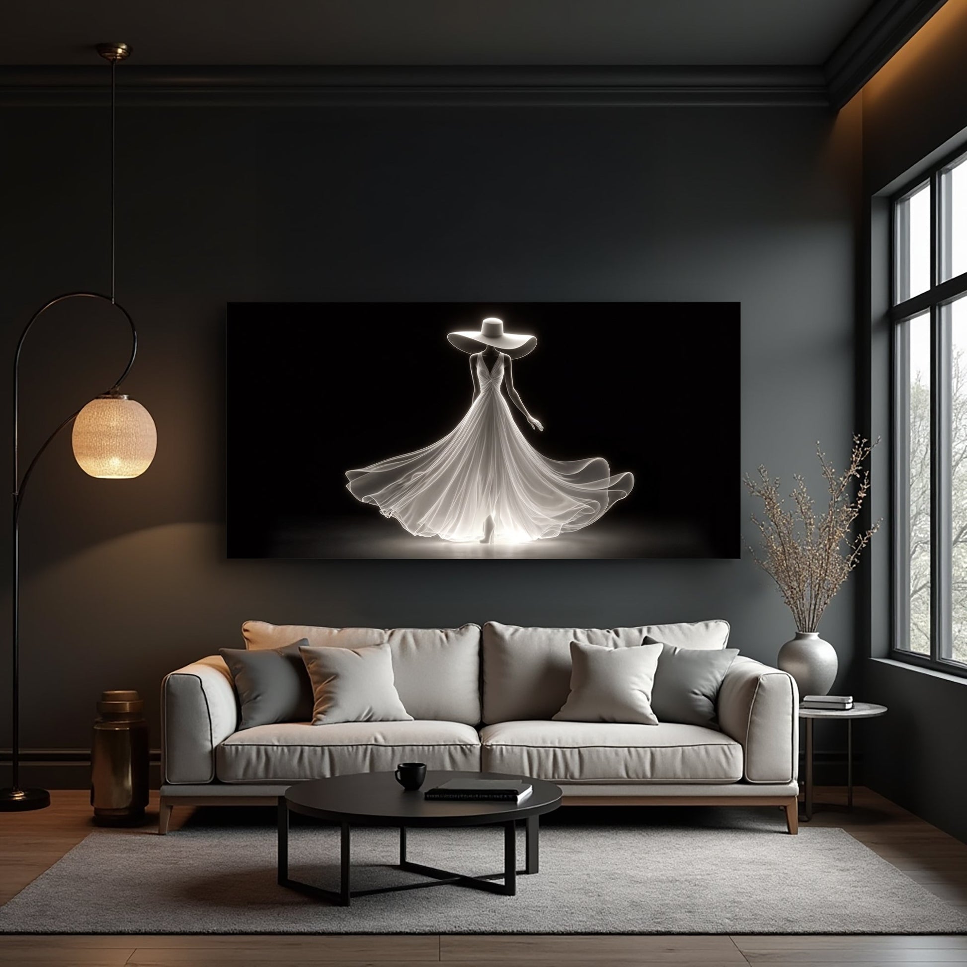 White gowned woman silhouette canvas art on black above a light gray sofa in a moody dark living room with a lit floor lamp