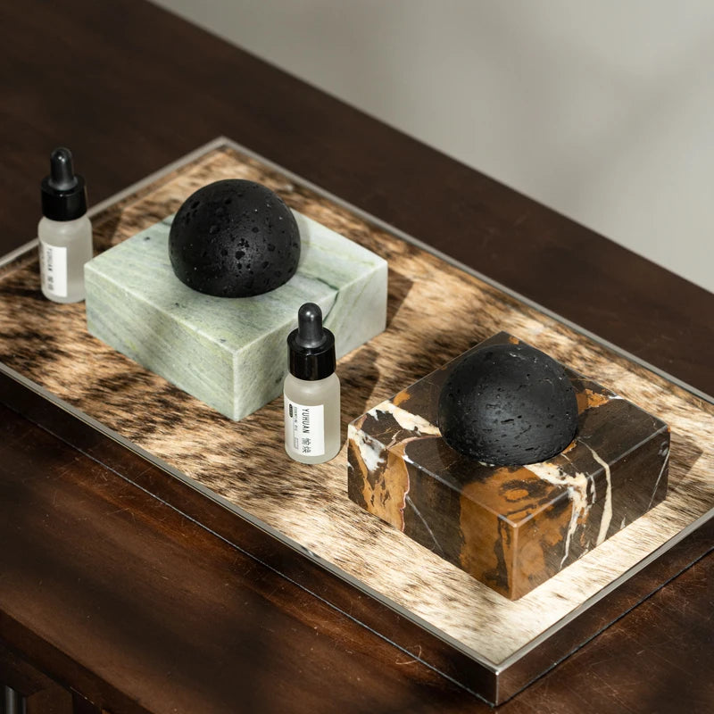 Black stone diffuser on a dark wooden tray with essential oils and candle