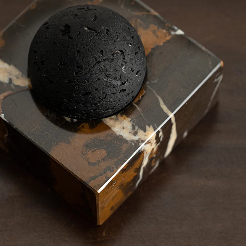 Close-up of the black volcanic stone resting on a travertine diffuser base
