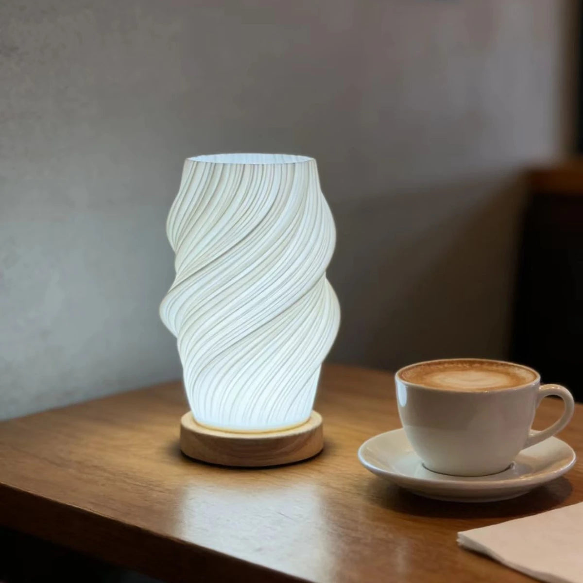 Spiral table lamp glowing warm on a café table beside a cup of cappuccino