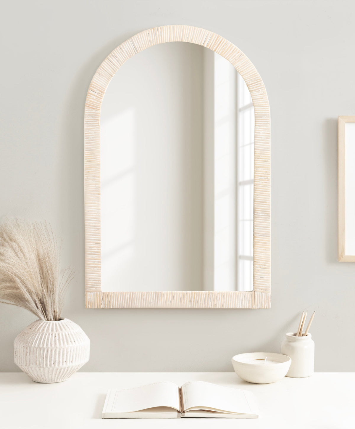 Natural rattan arched mirror styled on a console with pampas grass